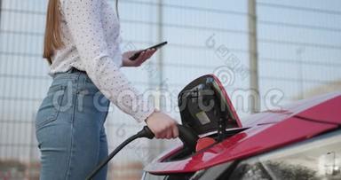 女人把电源插入电动汽车充电。 手接电力电缆至环保